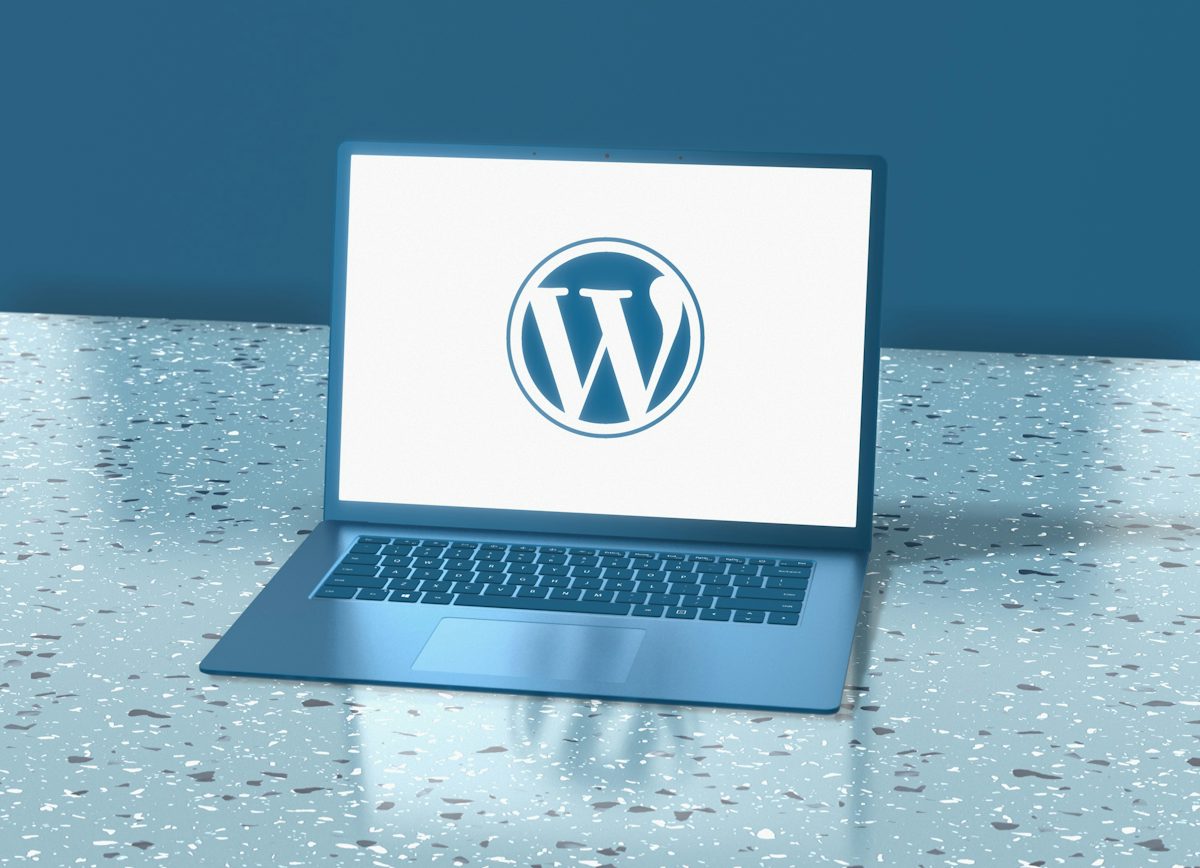 Blue laptop displaying the WordPress logo on a speckled blue surface
